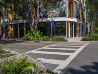 the street has a zebra crossing in front of it and many plants on the sidewalk