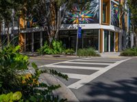 the street has a zebra crossing in front of it and many plants on the sidewalk