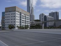 a wide empty parking lot in front of a tall office building with a bridge overhead