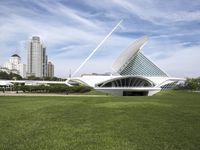 a large white structure is in the grass of the lawn in front of buildings and water