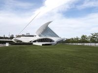 a large white structure is in the grass of the lawn in front of buildings and water