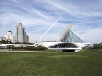 a large white structure is in the grass of the lawn in front of buildings and water