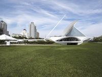 a large white structure is in the grass of the lawn in front of buildings and water