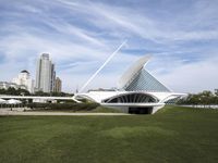 a large white structure is in the grass of the lawn in front of buildings and water