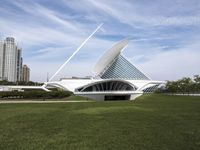 a large white structure is in the grass of the lawn in front of buildings and water