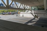 a person walking down the street in an empty parking lot under an open skyway