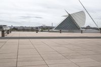 a long, wide white sculpture in front of some buildings on a river bank with water and sky