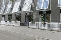 an open window store with a picketer fence on the sidewalk in front of it