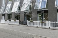 an open window store with a picketer fence on the sidewalk in front of it