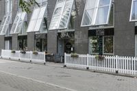 an open window store with a picketer fence on the sidewalk in front of it