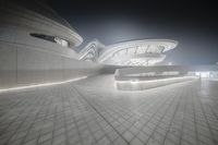 the modern architecture on this museum is lit up at night, with its circular shaped roof, floor and facade made of stone