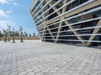 the building with windows is located near a sidewalk near a park with some trees and bushes