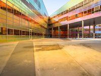 a building with several different colored glass walls surrounding it that has an open street and walkway near the entrance