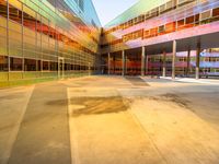 a building with several different colored glass walls surrounding it that has an open street and walkway near the entrance