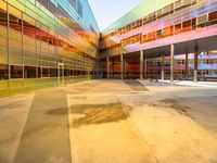 a building with several different colored glass walls surrounding it that has an open street and walkway near the entrance