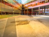 a building with several different colored glass walls surrounding it that has an open street and walkway near the entrance