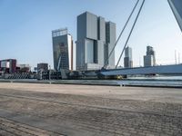 a bike riding along a waterway in a city with tall buildings in the background and a long bicycle on the right