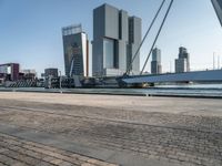 a bike riding along a waterway in a city with tall buildings in the background and a long bicycle on the right