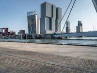 a bike riding along a waterway in a city with tall buildings in the background and a long bicycle on the right