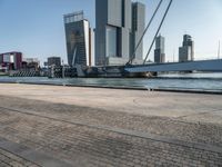 a bike riding along a waterway in a city with tall buildings in the background and a long bicycle on the right