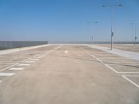 empty parking lot next to a fence and light posts, with empty road signs in it