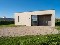 the small house is situated in the field and has wooden doors open to reveal it