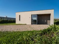 the small house is situated in the field and has wooden doors open to reveal it