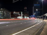 the road has many lanes going down it at night time with traffic passing by and buildings behind