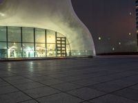 a night shot of people in the lobby of a building with a large glass wall