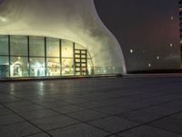 a night shot of people in the lobby of a building with a large glass wall