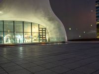 a night shot of people in the lobby of a building with a large glass wall