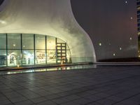 a night shot of people in the lobby of a building with a large glass wall