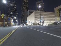 an empty empty street with some lights on at night in front of a modern structure