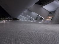 a very modern, shiny and empty building at night, with light shining through windows