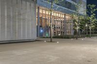 the entrance to a large building on the sidewalk is lit up at night as the lights shine