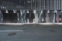 a parking garage with a red car parked in front of it at night next to the curb