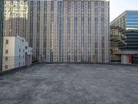 a large building in an empty lot with some buildings behind it and sky scrapes