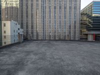 a large building in an empty lot with some buildings behind it and sky scrapes