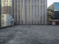 a large building in an empty lot with some buildings behind it and sky scrapes