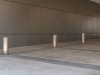 an empty walkway with a wall in the background with steel posts all around it on a building