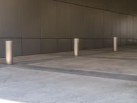 an empty walkway with a wall in the background with steel posts all around it on a building