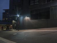 a building and a street light in the night time next to a sidewalk in a city