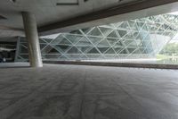 the walkway under the roof is lined with large glass panels and columns that provide ample access to the building