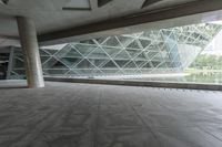 the walkway under the roof is lined with large glass panels and columns that provide ample access to the building