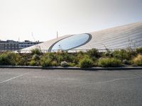 an airport parking lot near a stadium and a building with glass dome on top of it