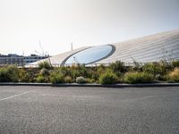 an airport parking lot near a stadium and a building with glass dome on top of it