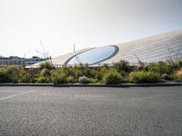 an airport parking lot near a stadium and a building with glass dome on top of it