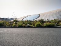 an airport parking lot near a stadium and a building with glass dome on top of it