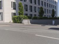 man riding a bike down the street in front of a large building with a red sign