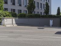 man riding a bike down the street in front of a large building with a red sign